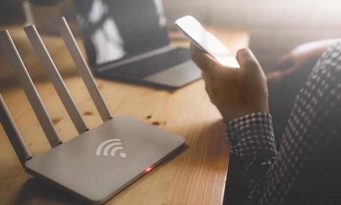 closeup of a wireless router and a man using smartphone on livin